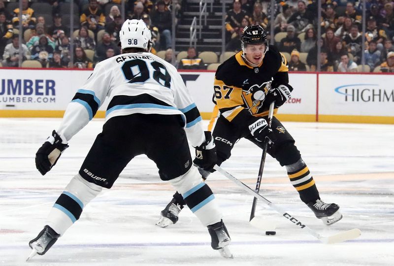 Nov 23, 2024; Pittsburgh, Pennsylvania, USA;  Pittsburgh Penguins right wing Rickard Rakell (67) skates up ice with the puck against Utah Hockey Club defenseman Mikhail Sergachev (98) during the first period at PPG Paints Arena. Mandatory Credit: Charles LeClaire-Imagn Images