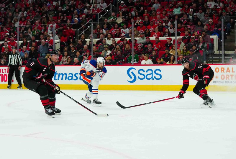 Nov 22, 2023; Raleigh, North Carolina, USA; Edmonton Oilers center Leon Draisaitl (29) takes a shot between Carolina Hurricanes center Jordan Staal (11) and  defenseman Jaccob Slavin (74) during the second period at PNC Arena. Mandatory Credit: James Guillory-USA TODAY Sports