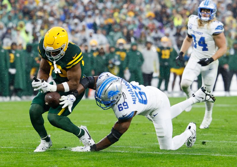 Green Bay Packers running back Chris Brooks (30) can't hang onto the ball against Detroit Lions linebacker Al-Quadin Muhammad (69) during the first half of an NFL football game Sunday, Nov. 3, 2024, in Green Bay, Wis. (AP Photo/Jeffrey Phelps