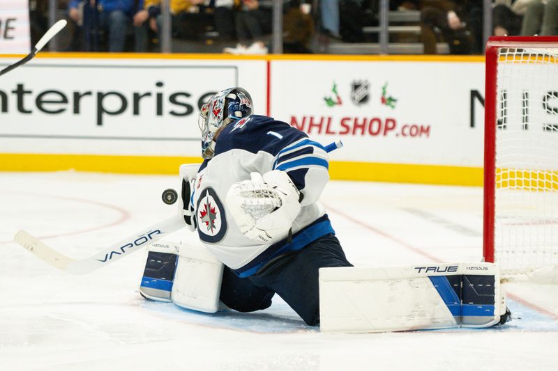 Nov 23, 2024; Nashville, Tennessee, USA;  Winnipeg Jets goaltender Eric Comrie (1) blocks the puck against the Nashville Predators during the third period at Bridgestone Arena. Mandatory Credit: Steve Roberts-Imagn Images