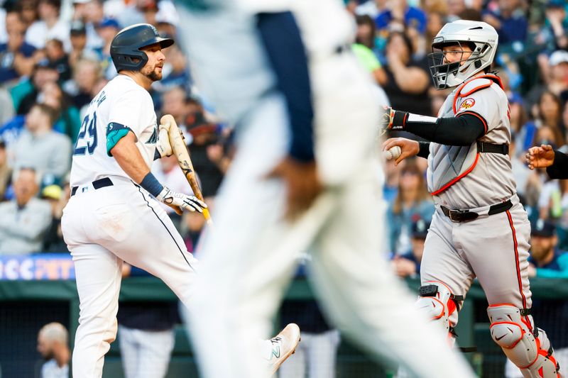 Jul 2, 2024; Seattle, Washington, USA; Seattle Mariners catcher Cal Raleigh (29) strikes out to en the sixth inning at T-Mobile Park. Baltimore Orioles catcher Adley Rutschman (35) stands at right. Mandatory Credit: Joe Nicholson-USA TODAY Sports