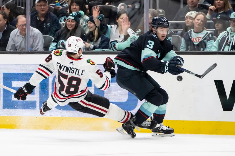 Jan 24, 2024; Seattle, Washington, USA; Seattle Kraken defenseman Will Borgen (3) knocks Chicago Blackhawks forward MacKenzie Entwistle (58) to the ice during the second period at Climate Pledge Arena. Mandatory Credit: Stephen Brashear-USA TODAY Sports