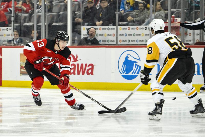 Apr 2, 2024; Newark, New Jersey, USA; New Jersey Devils defenseman Luke Hughes (43) skates with the puck while being defended by Pittsburgh Penguins defenseman Kris Letang (58) during the second period at Prudential Center. Mandatory Credit: John Jones-USA TODAY Sports