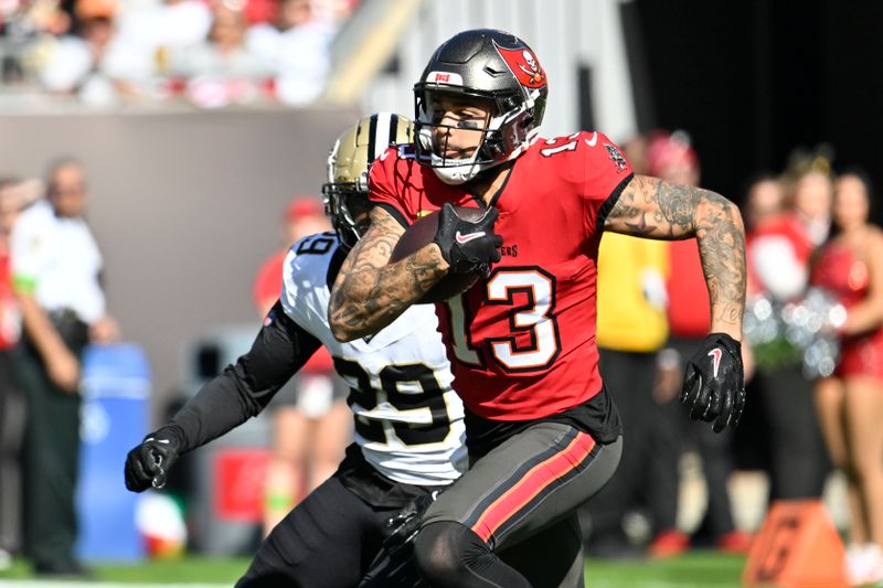 Tampa Bay Buccaneers wide receiver Mike Evans (13) carries against New Orleans Saints cornerback Paulson Adebo (29) in the first half of an NFL football game in Tampa, Fla., Sunday, Dec. 31, 2023. (AP Photo/Jason Behnken)