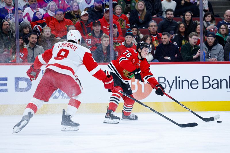 Dec 13, 2025; Chicago, Illinois, USA; Chicago Blackhawks left wing Nick Lardis (76) passes the puck against Detroit Red Wings defenseman Ben Chiarot (8) during the first period at United Center. Mandatory Credit: Kamil Krzaczynski-Imagn Images