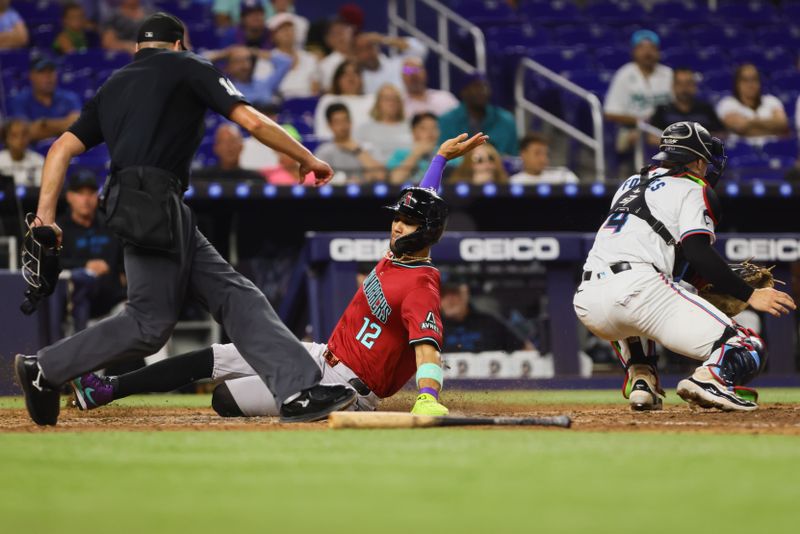 Aug 19, 2024; Miami, Florida, USA; Arizona Diamondbacks left fielder Lourdes Gurriel Jr. (12) slides at home plate and scores after an RBI single by catcher Adrian Del Castillo (not pictured) against the Miami Marlins during the seventh inning at loanDepot Park. Mandatory Credit: Sam Navarro-USA TODAY Sports