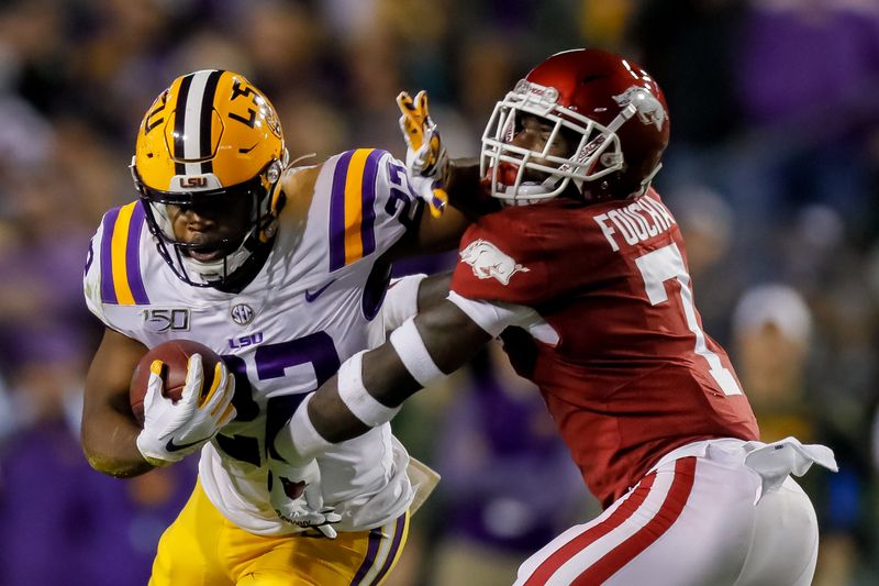 Nov 23, 2019; Baton Rouge, LA, USA; LSU Tigers running back Clyde Edwards-Helaire (22) carries the ball as Arkansas Razorbacks defensive back Joe Foucha (7) defends during the first half at Tiger Stadium. Mandatory Credit: Stephen Lew-USA TODAY Sports