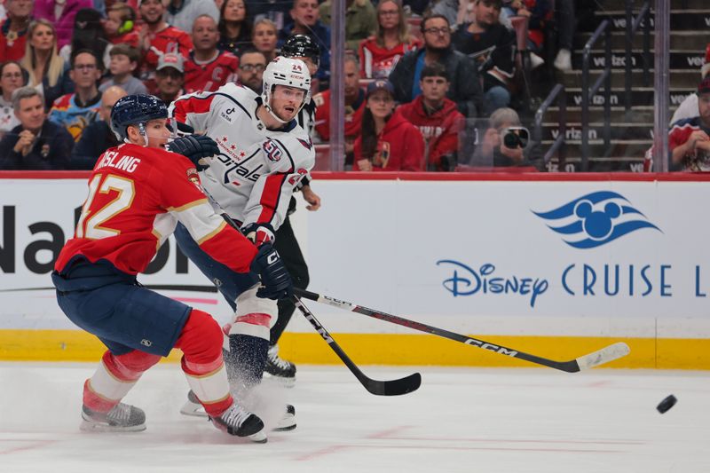 Nov 25, 2024; Sunrise, Florida, USA; Washington Capitals center Connor McMichael (24) shoots the puck as Florida Panthers defenseman Gustav Forsling (42) defends during the first period at Amerant Bank Arena. Mandatory Credit: Sam Navarro-Imagn Images