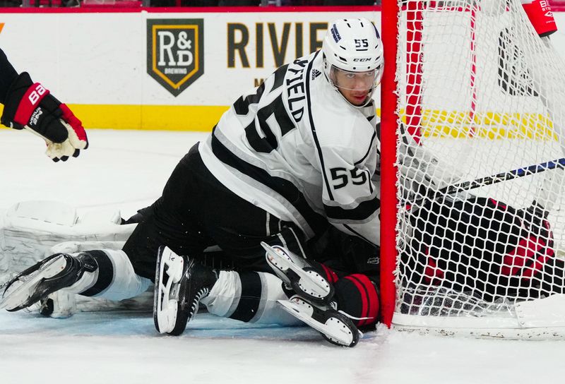 Jan 15, 2024; Raleigh, North Carolina, USA; Los Angeles Kings right wing Quinton Byfield (55) checks Carolina Hurricanes defenseman Brady Skjei (76) into the net during the third period at PNC Arena. Mandatory Credit: James Guillory-USA TODAY Sports