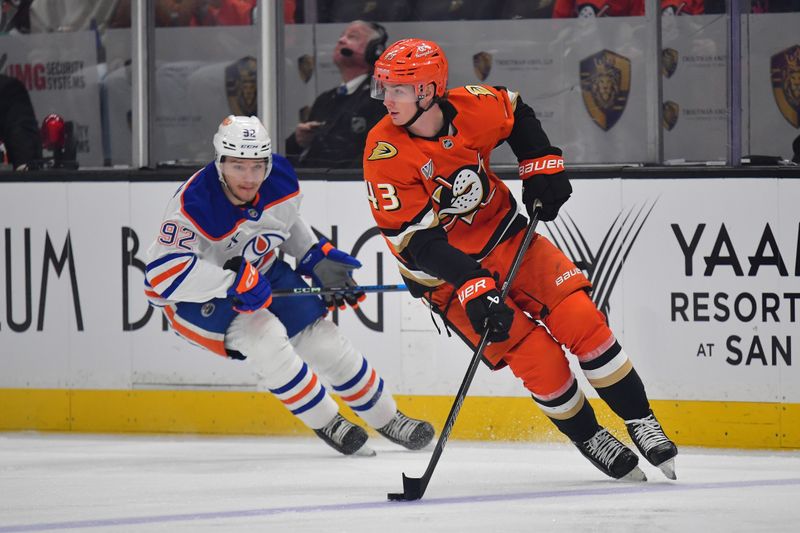 Apr 7, 2025; Anaheim, California, USA; Anaheim Ducks defenseman Drew Helleson (43) moves the puck against Edmonton Oilers right wing Vasily Podkolzin (92) during the first period at Honda Center. Mandatory Credit: Gary A. Vasquez-Imagn Images