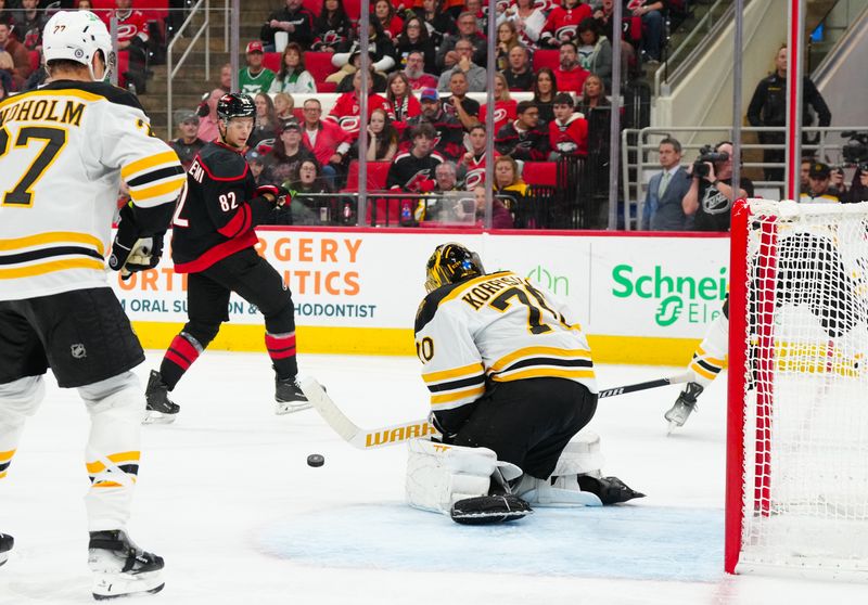 Oct 31, 2024; Raleigh, North Carolina, USA;  Boston Bruins goaltender Joonas Korpisalo (70) stops the shot by Carolina Hurricanes center Jesperi Kotkaniemi (82) during the third period at Lenovo Center. Mandatory Credit: James Guillory-Imagn Images