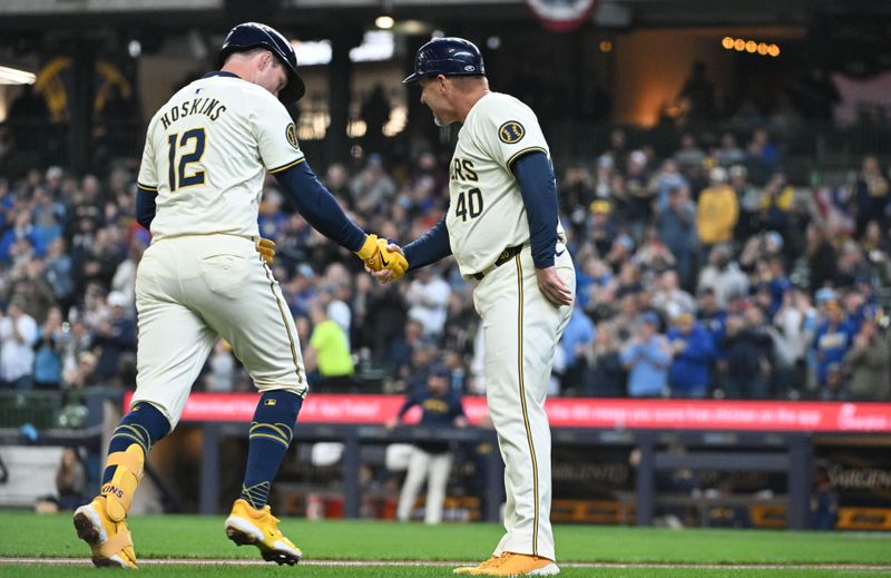 Apr 3, 2024; Milwaukee, Wisconsin, USA; Milwaukee Brewers first baseman Rhys Hoskins (12) is congratulated by third base coach Jason Lane after hitting a home run against the Minnesota Twins in the fourth inning at American Family Field. Mandatory Credit: Michael McLoone-USA TODAY Sports