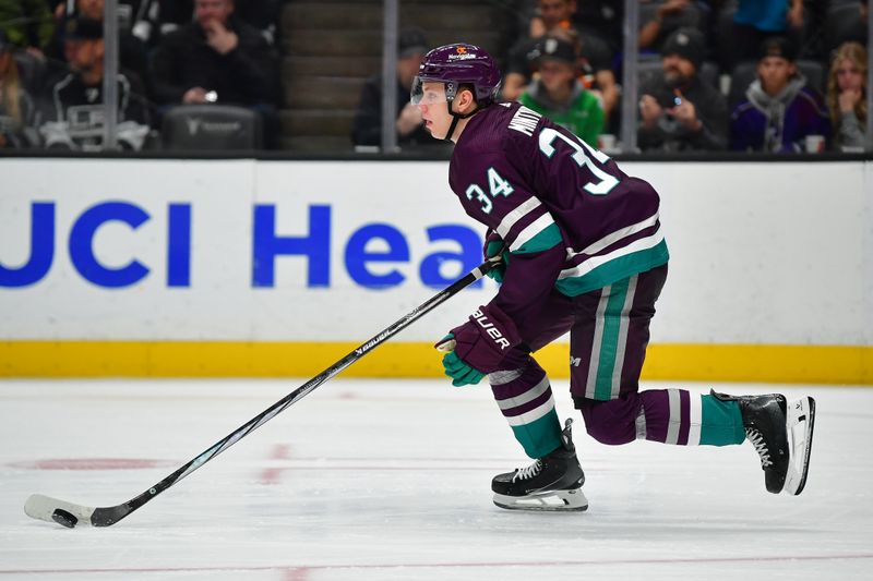 Nov 24, 2023; Anaheim, California, USA; Anaheim Ducks defenseman Pavel Mintyukov (34) moves the puck against the Los Angeles Kings during the third period at Honda Center. Mandatory Credit: Gary A. Vasquez-USA TODAY Sports