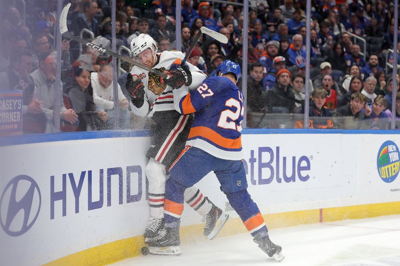 Mar 24, 2026; Elmont, New York, USA; New York Islanders left wing Anders Lee (27) checks Chicago Blackhawks defenseman Sam Rinzel (6) into the boards during the third period at UBS Arena. Mandatory Credit: Brad Penner-Imagn Images