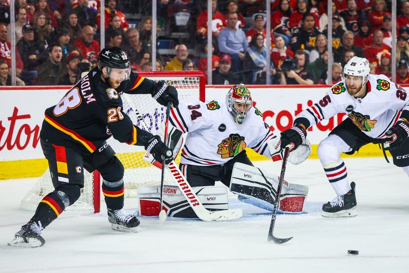 Jan 27, 2024; Calgary, Alberta, CAN; Calgary Flames center Elias Lindholm (28) controls the puck in front of Chicago Blackhawks goaltender Petr Mrazek (34) during the second period at Scotiabank Saddledome. Mandatory Credit: Sergei Belski-USA TODAY Sports