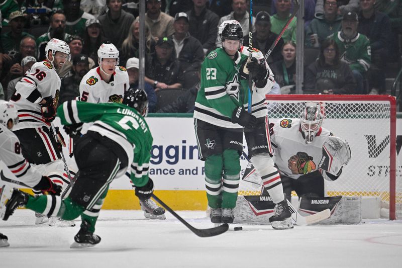 Nov 7, 2024; Dallas, Texas, USA; Dallas Stars defenseman Nils Lundkvist (5) shoots the puck as defenseman Esa Lindell (23) screens Chicago Blackhawks goaltender Arvid Soderblom (40) during the first period at the American Airlines Center. Mandatory Credit: Jerome Miron-Imagn Images