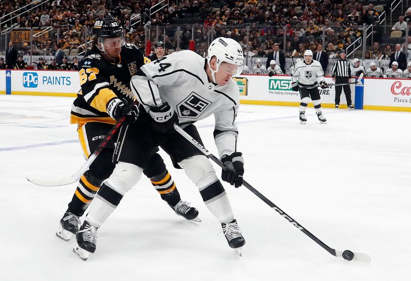 Feb 18, 2024; Pittsburgh, Pennsylvania, USA;  Los Angeles Kings defenseman Mikey Anderson (44) handles the puck against  pressure by Pittsburgh Penguins right wing Rickard Rakell (67) during the third period at PPG Paints Arena. Los Angeles won 2-1. Mandatory Credit: Charles LeClaire-USA TODAY Sports