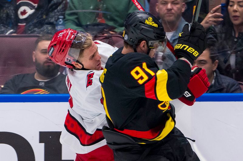 Oct 28, 2024; Vancouver, British Columbia, CAN; Vancouver Canucks forward Daniel Sprong (91) checks Carolina Hurricanes forward Jack Drury (18) during the third period at Rogers Arena. Mandatory Credit: Bob Frid-Imagn Images