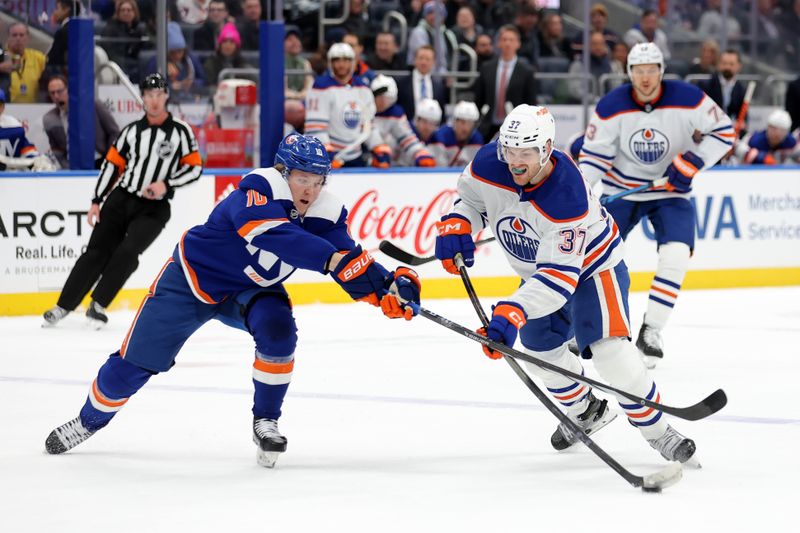 Dec 19, 2023; Elmont, New York, USA; Edmonton Oilers left wing Warren Foegele (37) controls the puck against New York Islanders right wing Simon Holmstrom (10) during the first period at UBS Arena. Mandatory Credit: Brad Penner-USA TODAY Sports