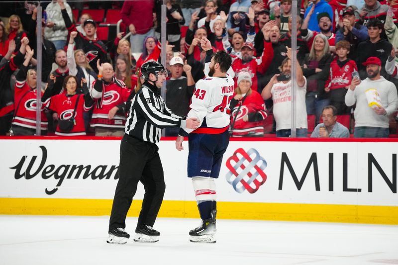 Apr 2, 2025; Raleigh, North Carolina, USA;  Washington Capitals right wing Tom Wilson (43) is escorted by linesman James Tobias (61) after his game misconducted against the Carolina Hurricanes during the third period at Lenovo Center. Mandatory Credit: James Guillory-Imagn Images