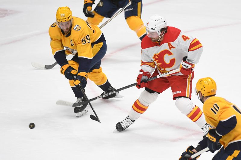 Jan 4, 2024; Nashville, Tennessee, USA; Calgary Flames defenseman Rasmus Andersson (4) scores as he is defended by Nashville Predators defenseman Roman Josi (59) during the first period at Bridgestone Arena. Mandatory Credit: Christopher Hanewinckel-USA TODAY Sports