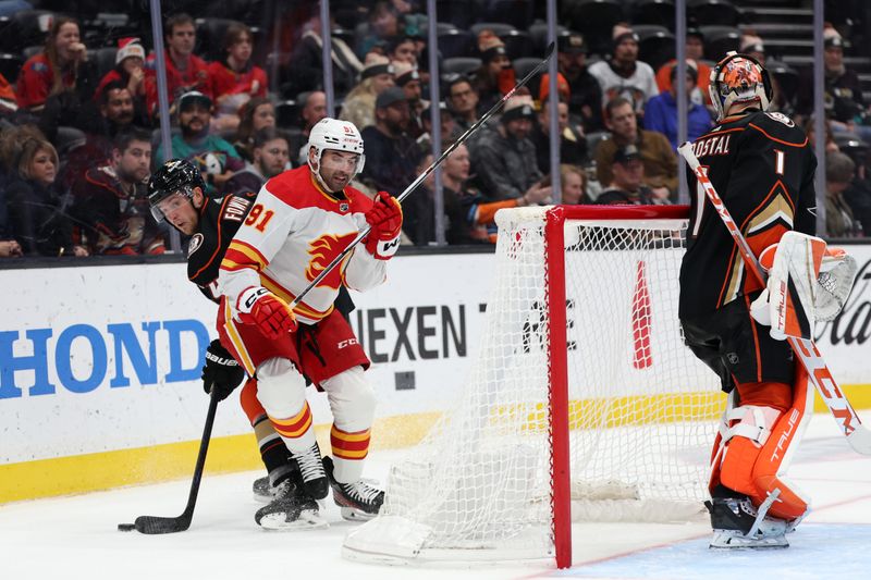 Dec 21, 2023; Anaheim, California, USA;  Calgary Flames center Nazem Kadri (91) fights for the puck against Anaheim Ducks defenseman Cam Fowler (4) during the third period at Honda Center. Mandatory Credit: Kiyoshi Mio-USA TODAY Sports