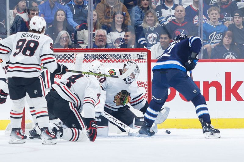 Oct 11, 2024; Winnipeg, Manitoba, CAN;  Chicago Blackhawks goalie Arvid Soderblom (40) makes a save on a shot by Winnipeg Jets forward Nino Niederreiter (62) during the first period at Canada Life Centre. Mandatory Credit: Terrence Lee-Imagn Images