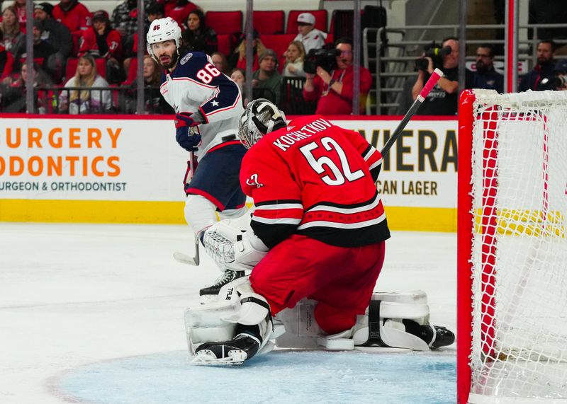 Nov 26, 2023; Raleigh, North Carolina, USA;  Carolina Hurricanes goaltender Pyotr Kochetkov (52) makes save in front of Columbus Blue Jackets left wing Kirill Marchenko (86) during the second period at PNC Arena. Mandatory Credit: James Guillory-USA TODAY Sports