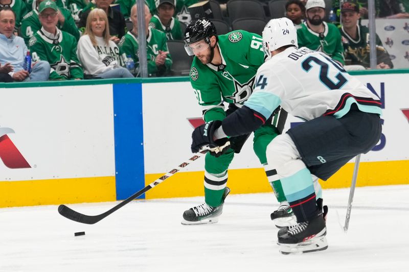 Oct 13, 2024; Dallas, Texas, USA;  Dallas Stars center Tyler Seguin (91) controls the puck as Seattle Kraken defenseman Jamie Oleksiak (24) defends during the second period at American Airlines Center. Mandatory Credit: Chris Jones-Imagn Images