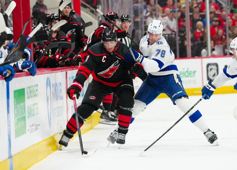 Mar 11, 2025; Raleigh, North Carolina, USA;  Carolina Hurricanes center Jordan Staal (11) is checked by Tampa Bay Lightning defenseman Emil Lilleberg (78) during the first period at Lenovo Center. Mandatory Credit: James Guillory-Imagn Images