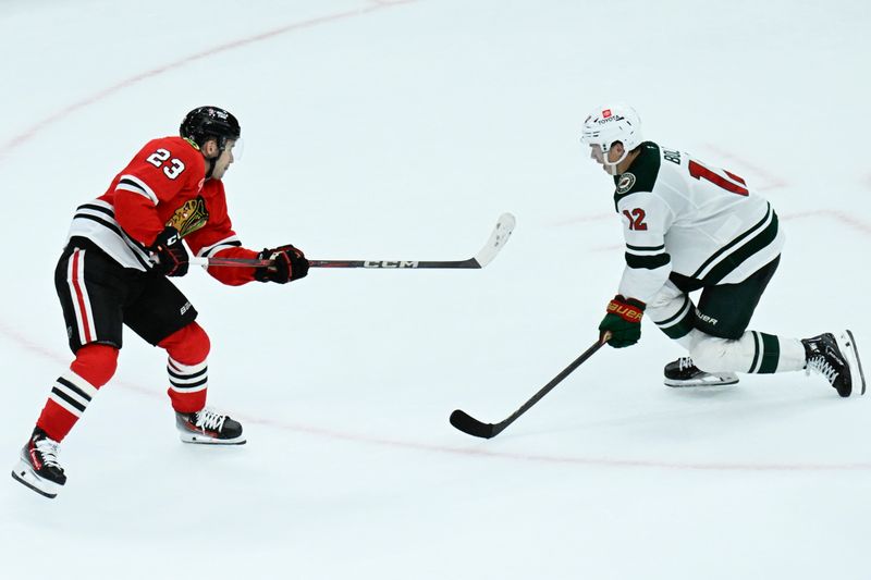 Nov 10, 2024; Chicago, Illinois, USA;  Chicago Blackhawks center Philipp Kurashev (23) scores the game winning goal past Minnesota Wild left wing Matt Boldy (12) during the overtime  period at the United Center. Mandatory Credit: Matt Marton-Imagn Images