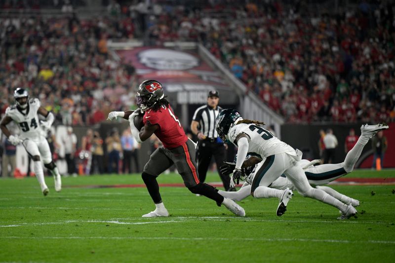 Tampa Bay Buccaneers running back Rachaad White (1) runs after catching a pass in front of Philadelphia Eagles cornerback Bradley Roby (33) and cornerback James Bradberry, right, during the first half of an NFL wild-card playoff football game, Monday, Jan. 15, 2024, in Tampa, Fla. (AP Photo/Phelan M. Ebenhack)