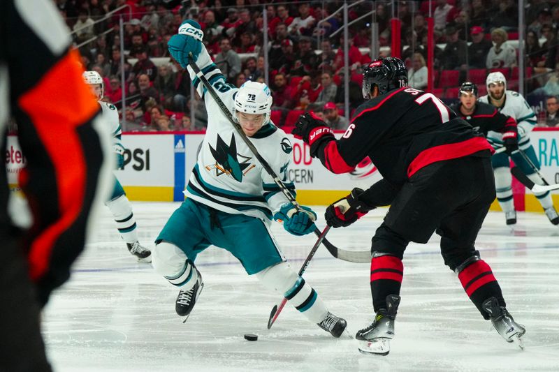 Oct 27, 2023; Raleigh, North Carolina, USA; San Jose Sharks center William Eklund (72) tries to cut with the puck past Carolina Hurricanes defenseman Dmitry Orlov (7) during the second period  at PNC Arena. Mandatory Credit: James Guillory-USA TODAY Sports