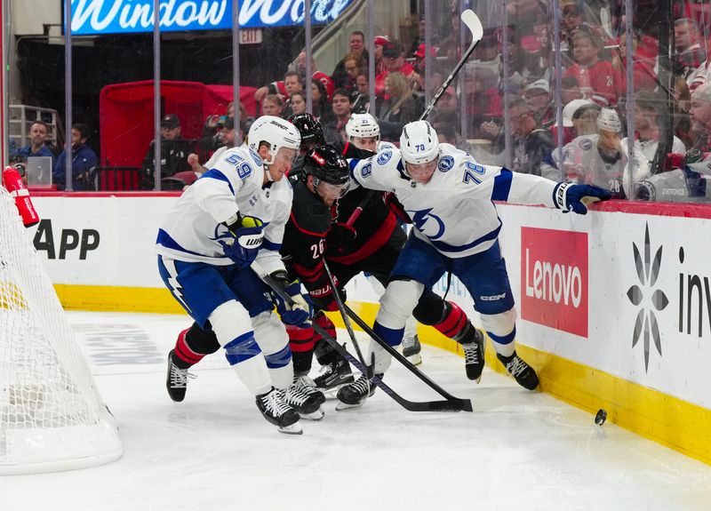 Oct 11, 2024; Raleigh, North Carolina, USA;  Tampa Bay Lightning center Jake Guentzel (59) defenseman Emil Lilleberg (78) and Carolina Hurricanes defenseman Sean Walker (26) battle for the puck during the second period at PNC Arena. Mandatory Credit: James Guillory-Imagn Images