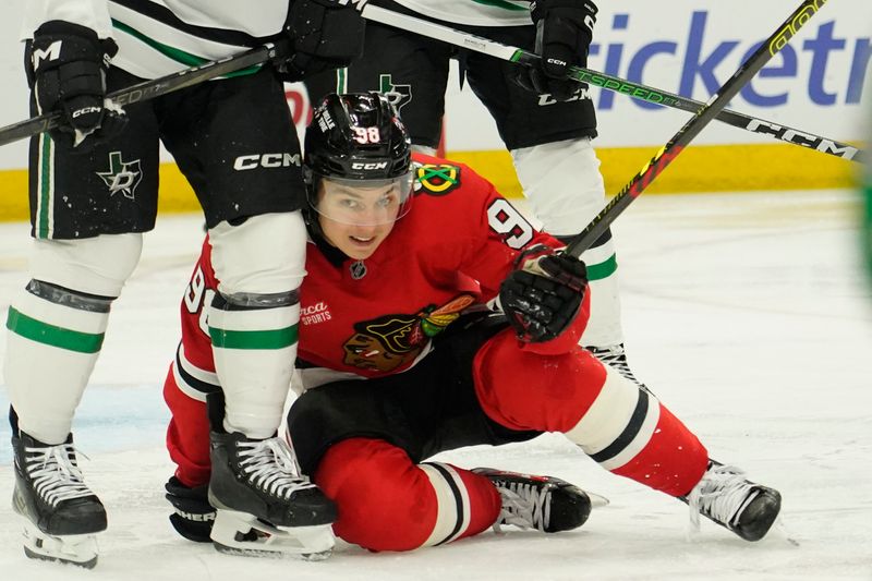 Nov 27, 2024; Chicago, Illinois, USA; Chicago Blackhawks center Connor Bedard (98) is knocked to the ice against the Dallas Stars during the third period at United Center. Mandatory Credit: David Banks-Imagn Images