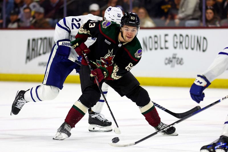 Feb 21, 2024; Tempe, Arizona, USA; Arizona Coyotes left wing Matias Maccelli (63) moves the puck against Toronto Maple Leafs defenseman Jake McCabe (22) during the second period at Mullett Arena. Mandatory Credit: Mark J. Rebilas-USA TODAY Sports