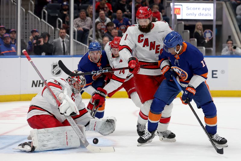 Jan 25, 2025; Elmont, New York, USA; Carolina Hurricanes goaltender Pyotr Kochetkov (52) plays the puck against New York Islanders center Kyle Palmieri (21) and left wing Anthony Duclair (11) in front of Hurricanes defensemen Jaccob Slavin (74) and Brent Burns (8) during the first period at UBS Arena. Mandatory Credit: Brad Penner-Imagn Images