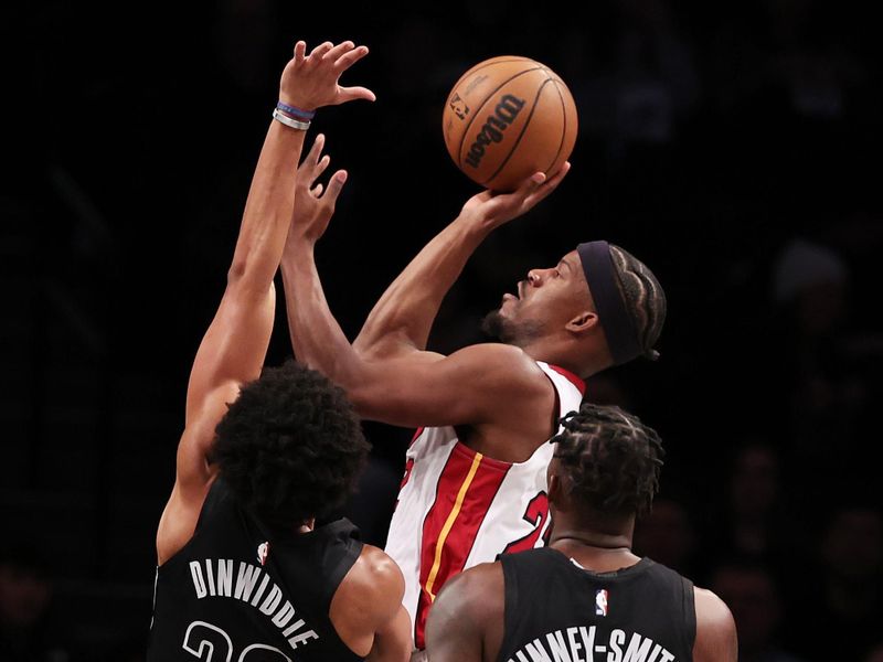 NEW YORK, NEW YORK - JANUARY 15:  Jimmy Butler #22 of the Miami Heat shoots against Spencer Dinwiddie #26 and Dorian Finney-Smith #28 of the Brooklyn Nets during their game at Barclays Center on January 15, 2024 in New York City.   User expressly acknowledges and agrees that, by downloading and or using this photograph, User is consenting to the terms and conditions of the Getty Images License Agreement.  (Photo by Al Bello/Getty Images)