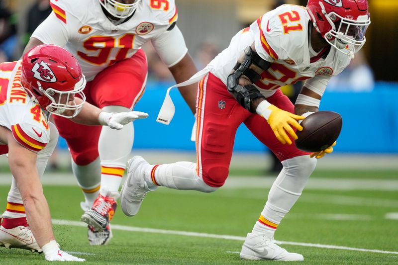 Kansas City Chiefs safety Mike Edwards (21) picks up a fumble before running it back for a touchdown during the first half of an NFL football game against the Los Angeles Chargers, Sunday, Jan. 7, 2024, in Inglewood, Calif. (AP Photo/Ashley Landis)