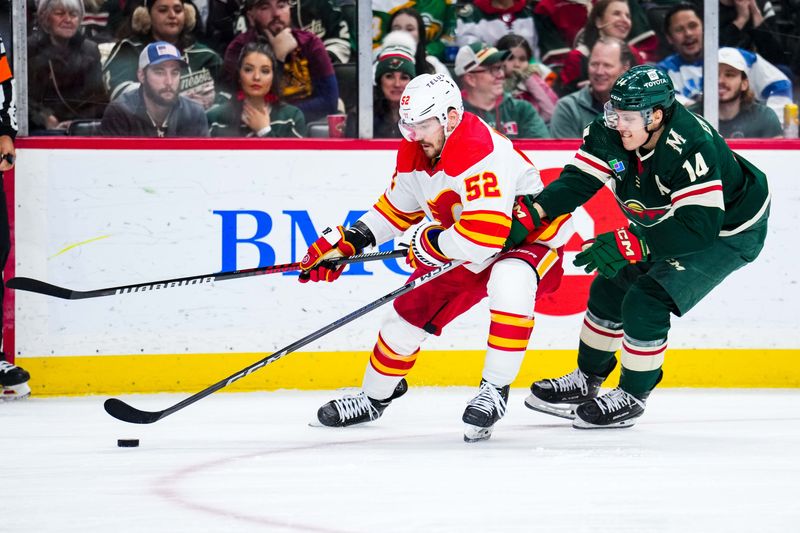 Jan 2, 2024; Saint Paul, Minnesota, USA; Calgary Flames defenseman MacKenzie Weegar (52) protects the puck from Minnesota Wild center Joel Eriksson Ek (14) during the second period at Xcel Energy Center. Mandatory Credit: Brace Hemmelgarn-USA TODAY Sports