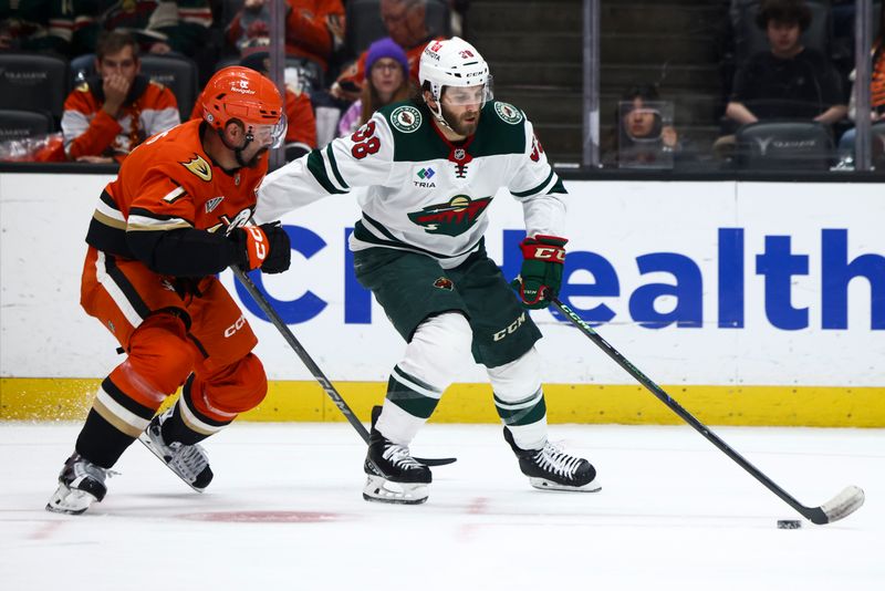 Nov 8, 2024; Anaheim, California, USA; Minnesota Wild right wing Ryan Hartman (38) skates with the puck during the third period of a hockey game against Anaheim Ducks defenseman Radko Gudas (7) at Honda Center. Mandatory Credit: Jessica Alcheh-Imagn Images