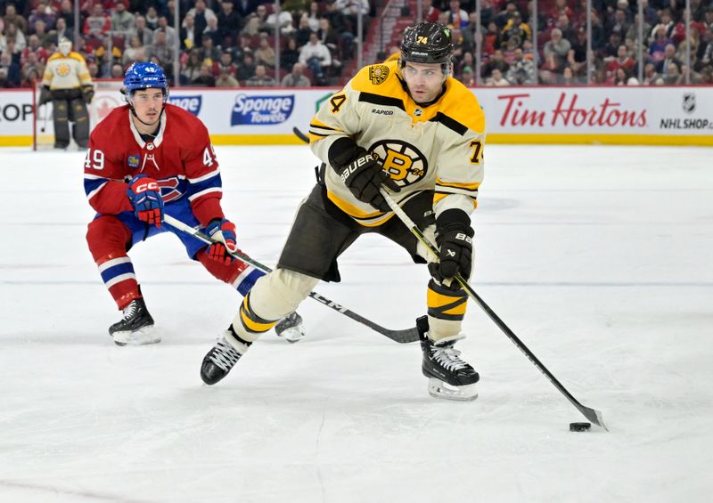 Mar 14, 2024; Montreal, Quebec, CAN; Boston Bruins forward Jake DeBrusk (74) plays the puck and Montreal Canadiens forward Rafael Harvey-Pinard (49) defends during the third period at the Bell Centre. Mandatory Credit: Eric Bolte-USA TODAY Sports