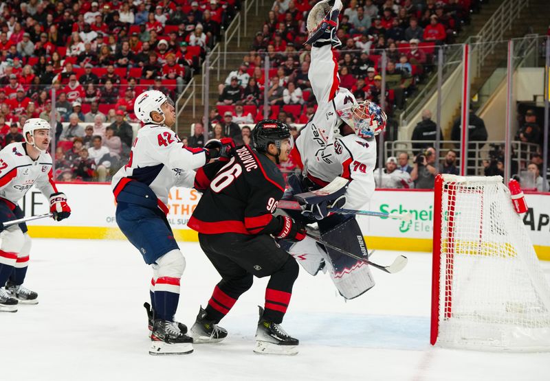 Nov 3, 2024; Raleigh, North Carolina, USA;  Washington Capitals goaltender Charlie Lindgren (79) reaches for the puck with defenseman Martin Fehervary (42) and Carolina Hurricanes defenseman Sean Walker (26) at Lenovo Center. Mandatory Credit: James Guillory-Imagn Images