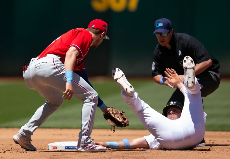 Jun 18, 2023; Oakland, California, USA; Oakland Athletics center fielder JJ Bleday (right) keeps his hand on the base as Philadelphia Phillies shortstop Trea Turner (7) applies the tag on a stolen base attempt during the fourth inning at Oakland-Alameda County Coliseum. Umpire is Brennan Miller. Mandatory Credit: D. Ross Cameron-USA TODAY Sports