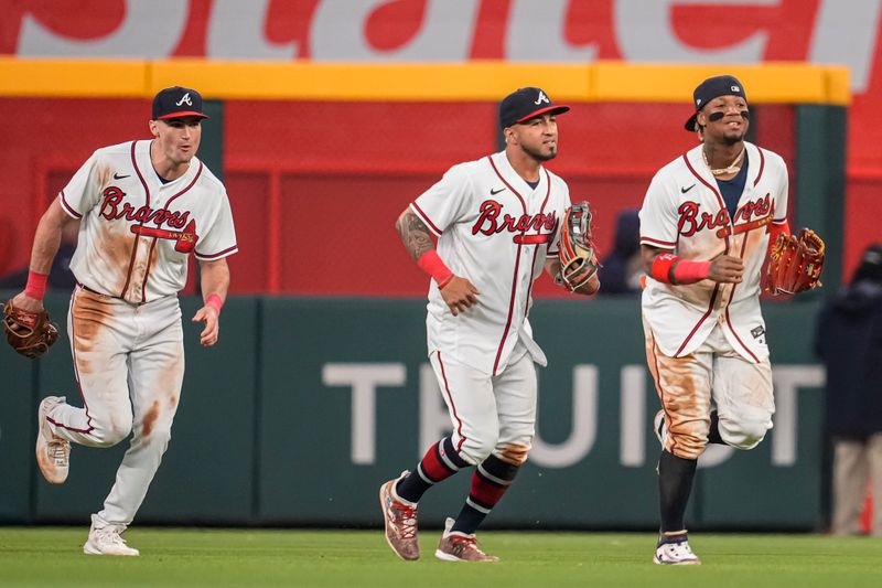 Apr 12, 2023; Cumberland, Georgia, USA; Atlanta Braves outfielders Sam Hilliard Eddie Rosario and Ronald Acuna Jr. react after defeating the Cincinnati Reds at Truist Park. Mandatory Credit: Dale Zanine-USA TODAY Sports