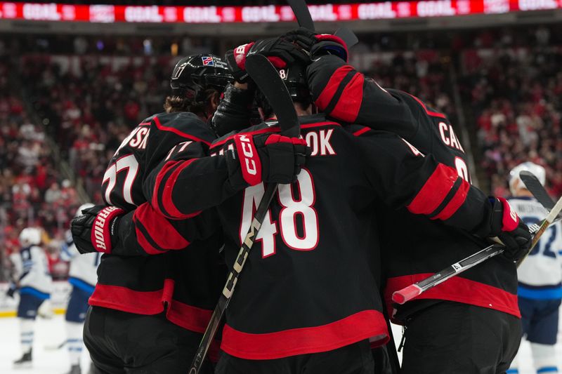 Nov 28, 2025; Raleigh, North Carolina, USA;  Carolina Hurricanes left wing Jordan Martinook (48) is congratulated by left wing Mark Jankowski (77) and left wing William Carrier (28) after his goal against the Winnipeg Jets during the third period at Lenovo Center. Mandatory Credit: James Guillory-Imagn Images