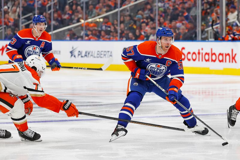 Mar 4, 2025; Edmonton, Alberta, CAN; Anaheim Ducks forward Frank Vatrano (77) tries to knock the puck away from Edmonton Oilers forward Connor McDavid (97) during the third period at Rogers Place. Mandatory Credit: Perry Nelson-Imagn Images