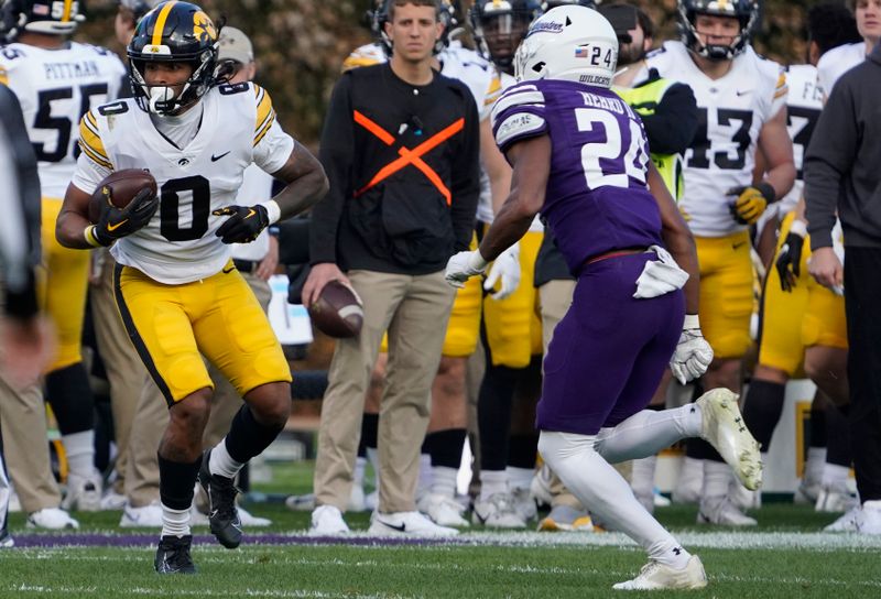 Nov 4, 2023; Chicago, Illinois, USA; Iowa Hawkeyes wide receiver Diante Vines (0) runs back a punt as Northwestern Wildcats defensive back Rod Heard II (24) defends during the first half at Wrigley Field. Mandatory Credit: David Banks-USA TODAY Sports