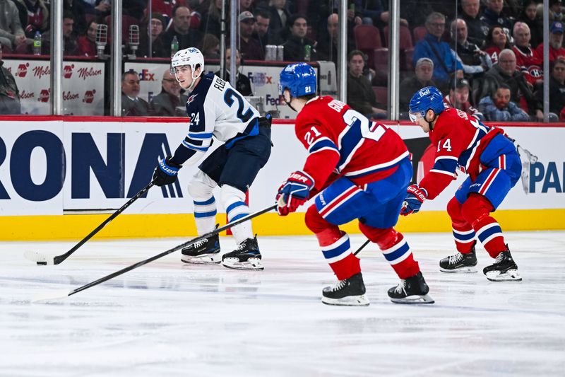 Jan 28, 2025; Montreal, Quebec, CAN; Winnipeg Jets defenseman Haydn Fleury (24) plays the puck against Montreal Canadiens defenseman Kaiden Guhle (21) and center Nick Suzuki (14) during the third period at Bell Centre. Mandatory Credit: David Kirouac-Imagn Images