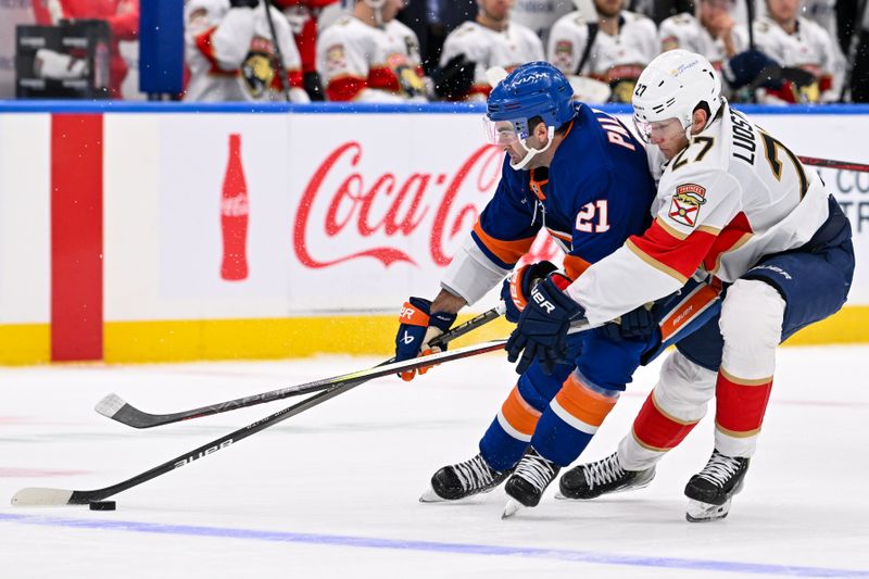 Oct 26, 2024; Elmont, New York, USA;  Florida Panthers center Eetu Luostarinen (27) defends against New York Islanders center Kyle Palmieri (21) during the third period at UBS Arena. Mandatory Credit: Dennis Schneidler-Imagn Images